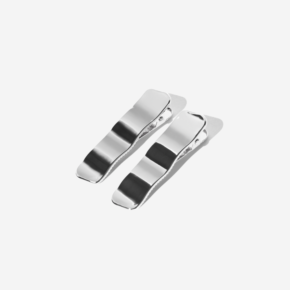 Two silver hair clips on a light gray background